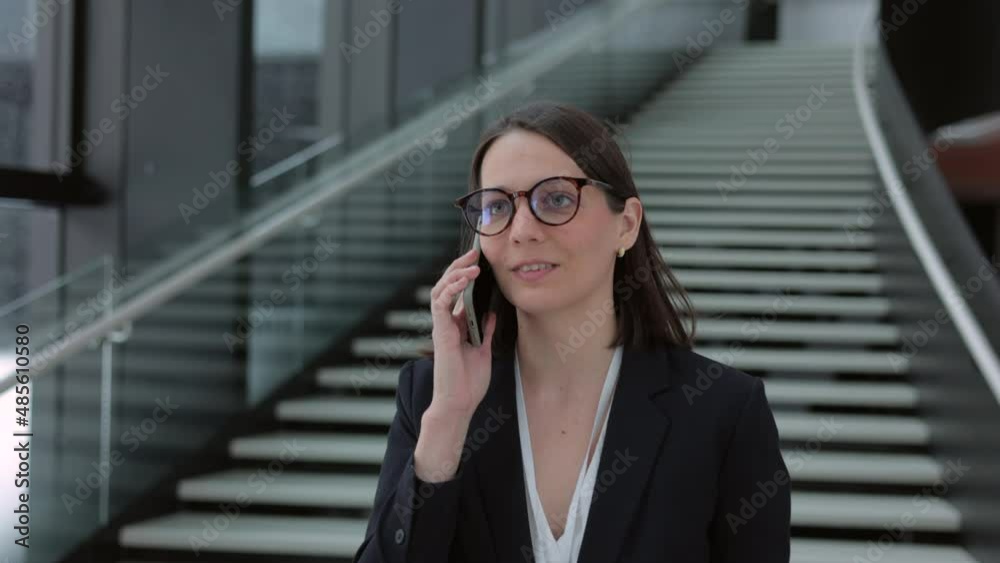 a business woman in a business suit with a suitcase walks through the airport or business center and talks on the phone. a European confident woman is a company director or a top manager at a business a business woman in a business suit with a suitcase walks through the airport or business center and talks on the phone. a European confident woman is a company director or a top manager at a business