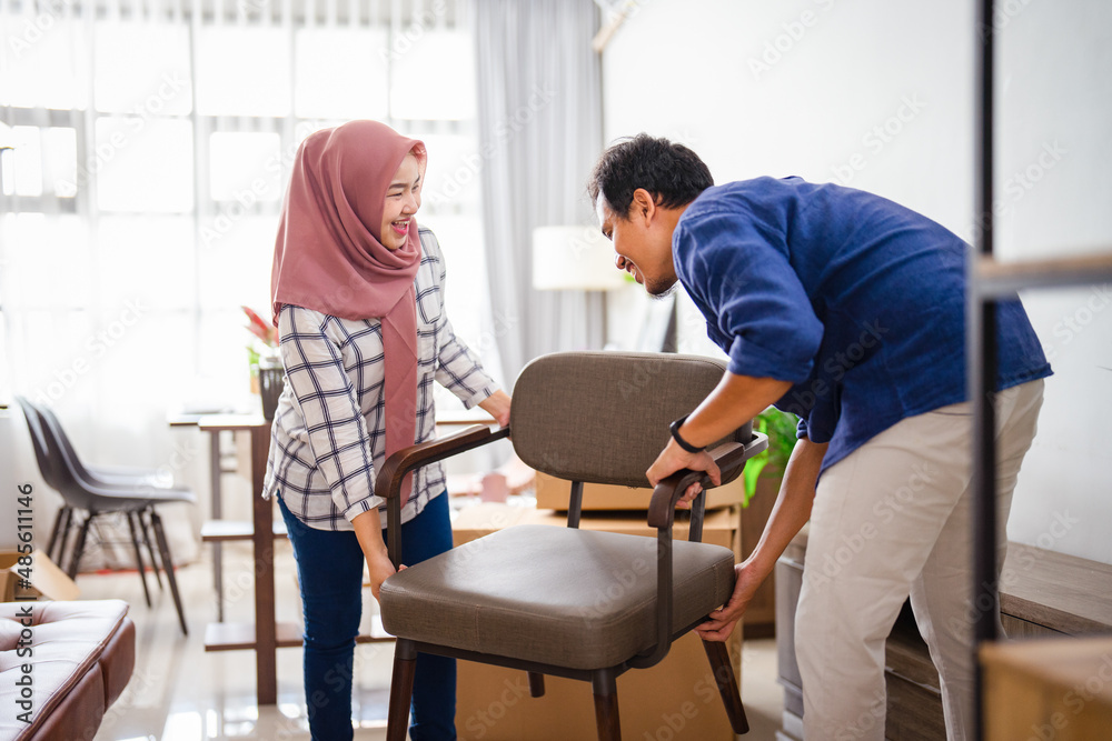 muslim young couple moving new chair at their new home muslim young couple moving new chair at their new home