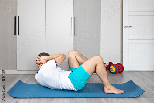 A strong, healthy man with muscles, training at home. Exercises for the muscles of the press