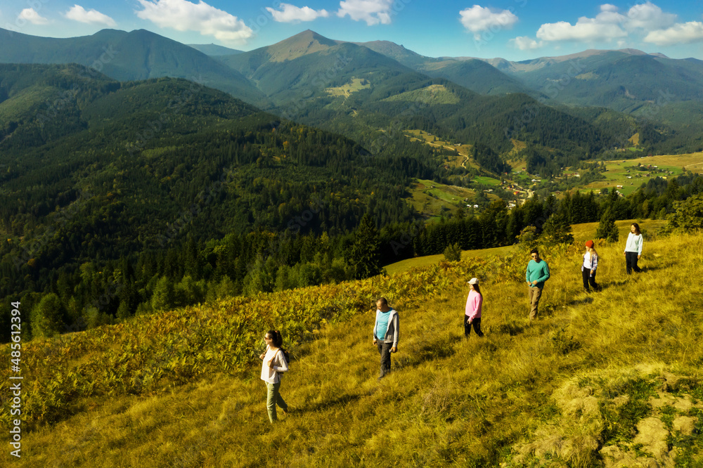 Naklejka premium Group of tourists walking on hill in mountains. Drone photography