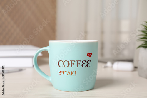 Mug with inscription Coffee Break on white wooden table in office