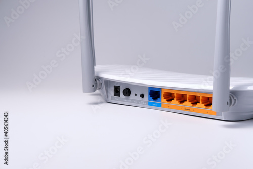 Wi-Fi router with RJ-45 connectors is isolated on a white-gray background on the right side, and copyspace on the left.