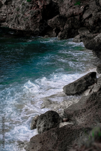 Bali ocean with foamy waves and dark stone cliffs