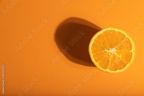 Ripe cut orange on orange pastel background. Top view, copy space, hard light.