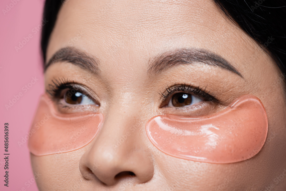 Fototapeta premium Cropped view of asian woman with eye patches looking away isolated on pink