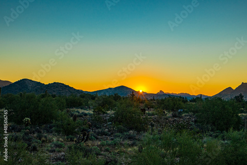 The sun peeks over the desert mountain at sunrise in Arizona