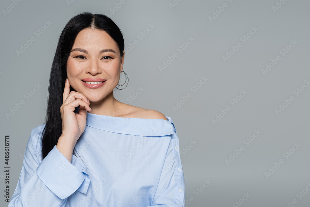 Positive asian woman in blouse looking at camera isolated on grey Positive asian woman in blouse looking at camera isolated on grey
