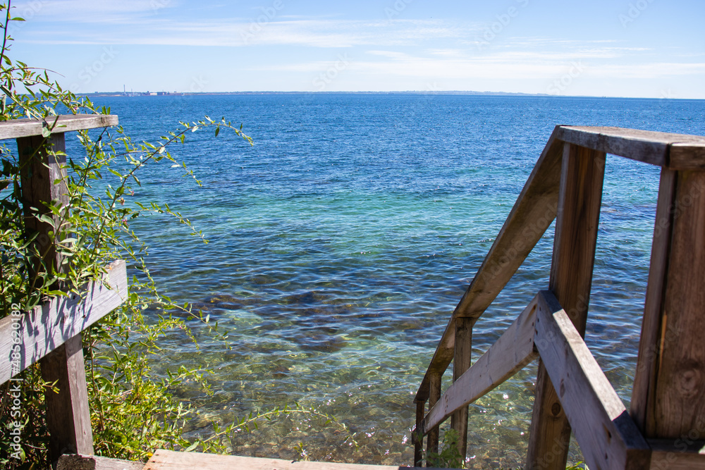 View of the blue sea on a quiet summer sunny day. Stairs to the sea. High quality photo