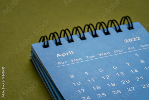 April 2022 - spiral desktop calendar, time and business concept