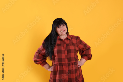 Beautiful overweight mature woman with charming smile on yellow background © New Africa