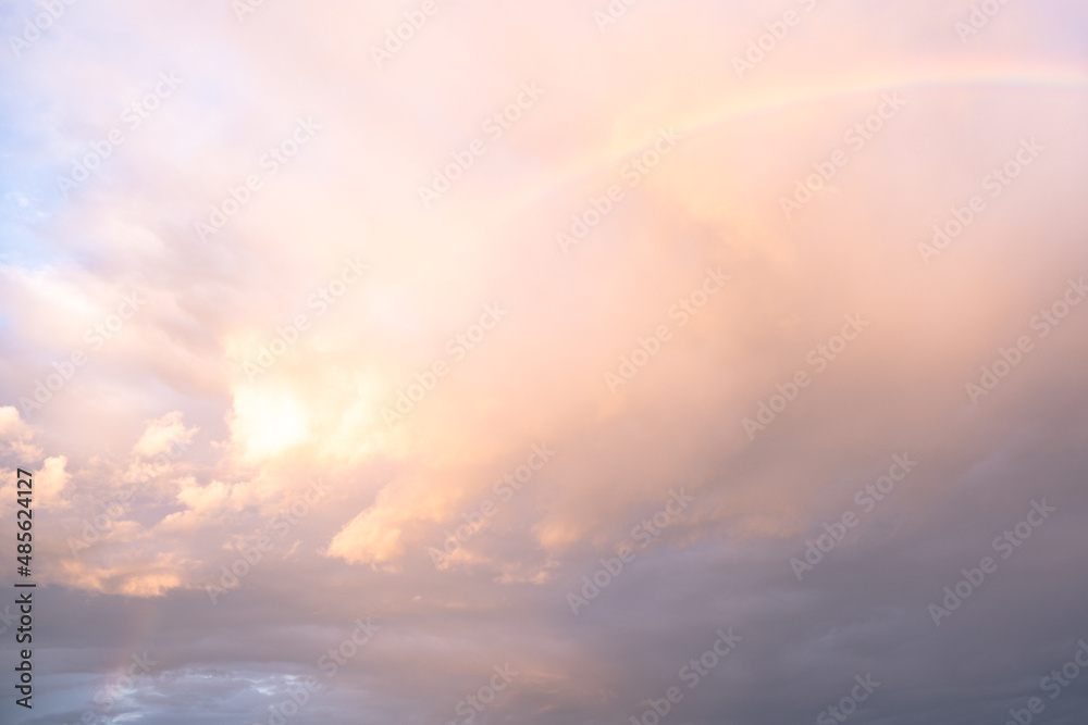 Feather clouds in delicate rainbow colors at the edge of a cumulus thundercloud