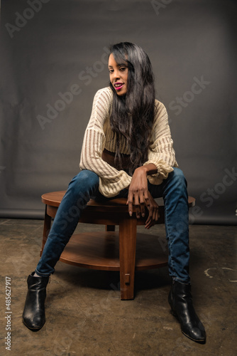 Tall and Glamorous BIPOC woman with long hair poses in a Los Angeles studio in jeans and a cropped sweater.
