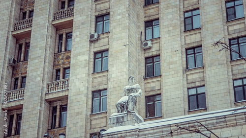 Statue of a man against the backdrop of a multi-storey building, photo during the day