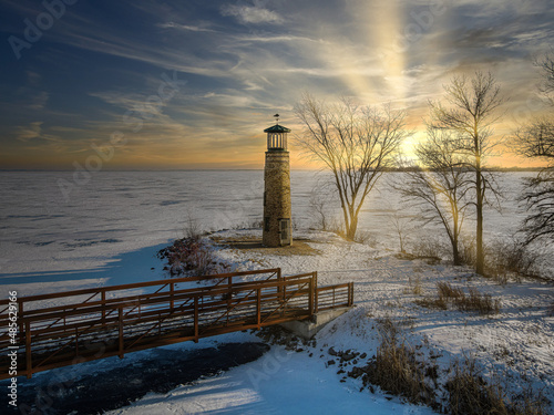 At the local park the old lighthouse still stands over the frozen lake photo