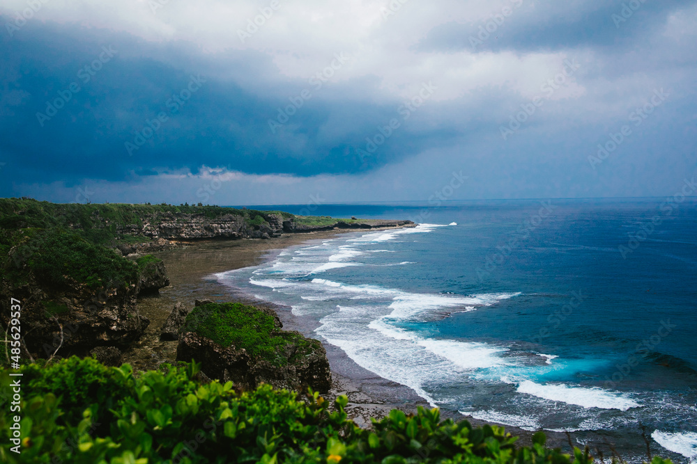 Obraz premium Storm rolls in over ocean and tropical island with waves and clouds