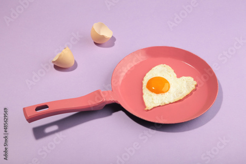 Pink frying pan and egg in heart shape. Valentine's day