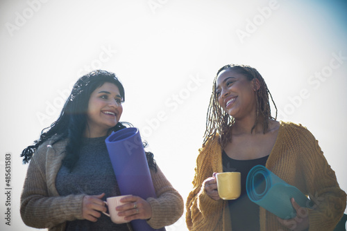 Happy young women friends with yoga mats and coffee cups photo