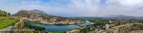 Wide-angle panorama of Buna river valley - view from the wall of the Rozafa castle in Shkoder, Albania. Delightful landscape with a water stream among mountains, fields and forests - view from above