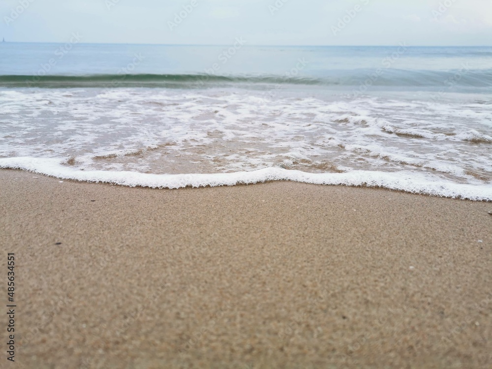 Detail of small waves arriving at the shore of the beach. Relaxation and peace