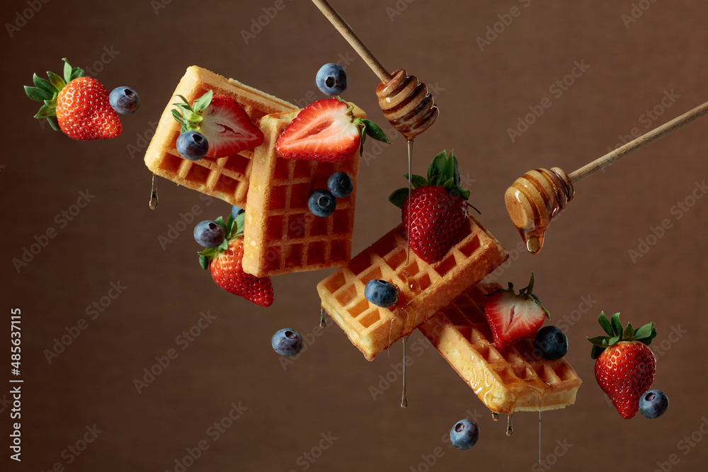 Waffles with blueberries, strawberries, and honey.