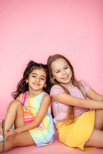 Funny little girls 7-10 years old in casual summer clothes posing on a solid pink background. The concept of a child's lifestyle. Layout of the copy space.