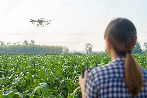 Foto Young smart farmer controlling drone spraying fertilizer and pesticide over farm