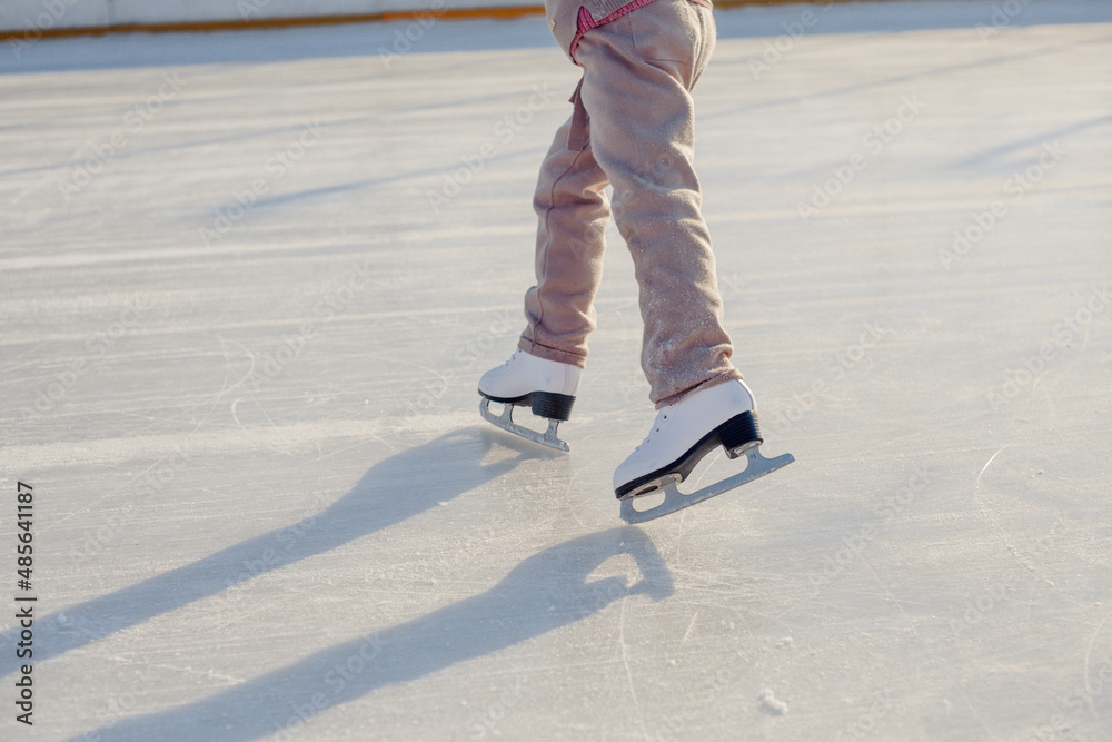 Funny little blonde girl of 7 years old in casual clothes posing on a skating rink in skates. The concept of a child's lifestyle. Layout of the copy space. Funny little blonde girl of 7 years old in casual clothes posing on a skating rink in skates. The concept of a child's lifestyle. Layout of the copy space.