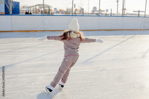 Funny little blonde girl of 7 years old in casual clothes posing on a skating rink in skates. The concept of a child's lifestyle. Layout of the copy space.