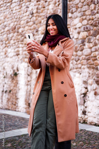 indian young woman using cellphone and laughing, vertical portrait