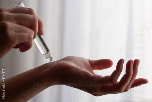 Closeup of a woman using rollerball perfume on her wrist.