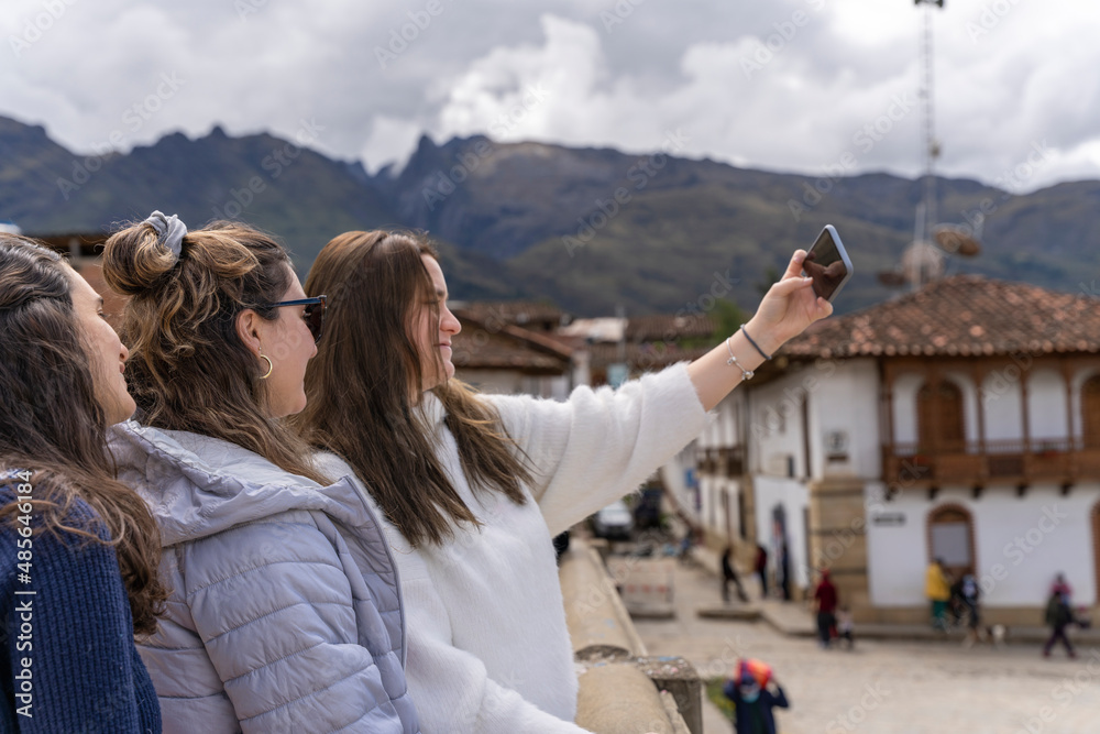 Three friends taking a selfie standing in a traditional andean town