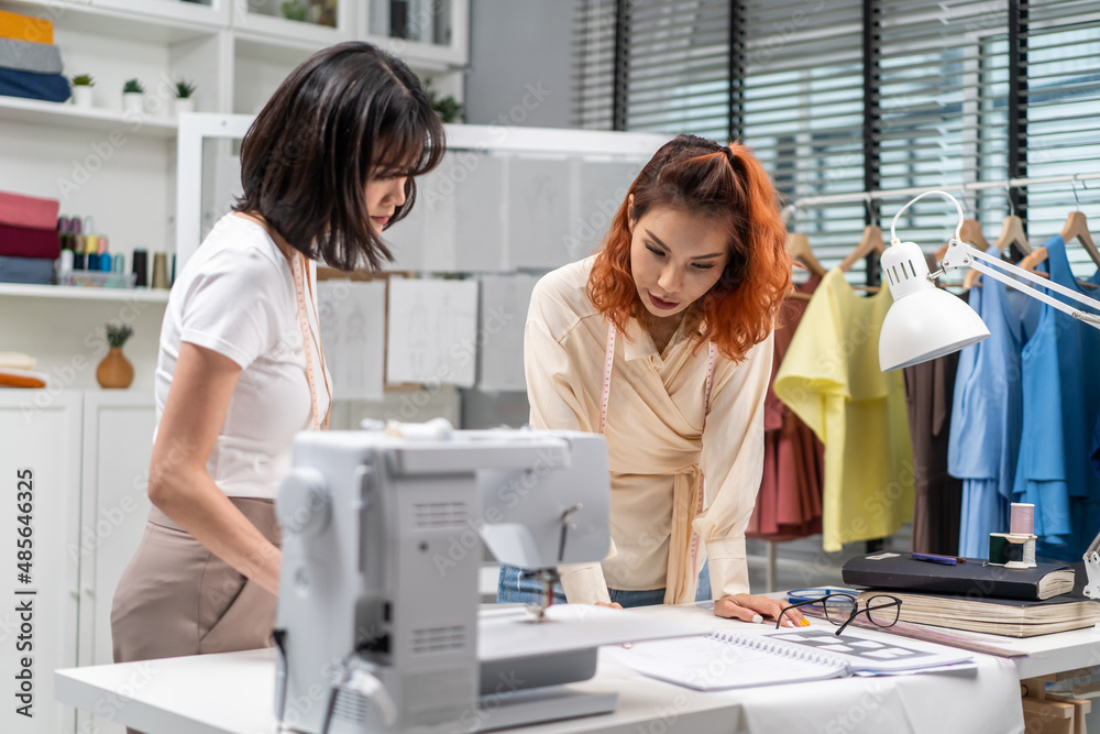 Obraz premium Asian two tailor woman working to design clothes in tailoring atelier. 