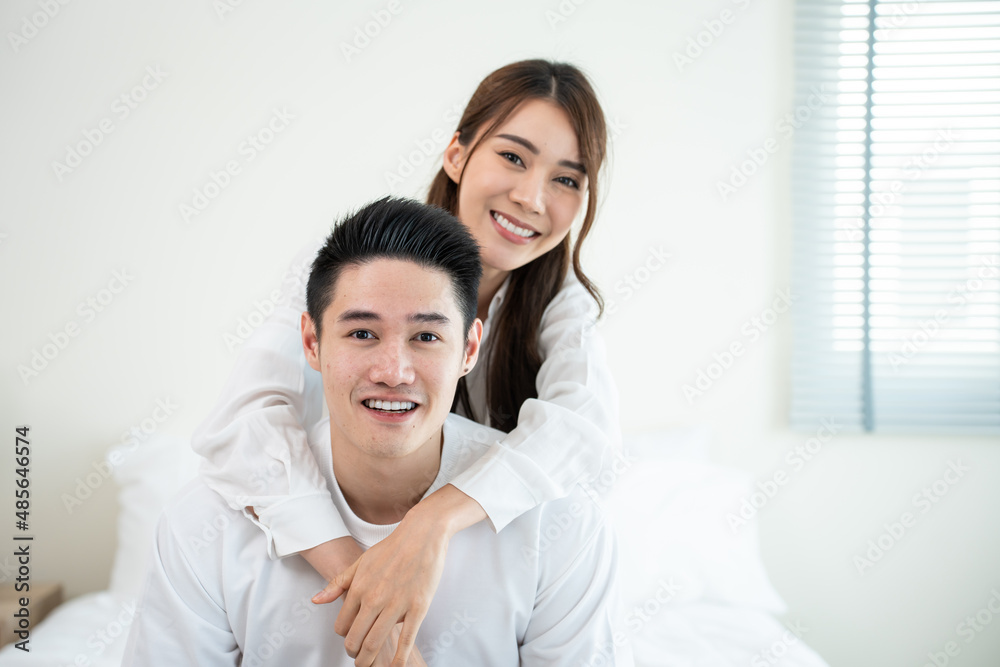 Portrait of Asian new marriage couple sit on bed and looking at camera. 
