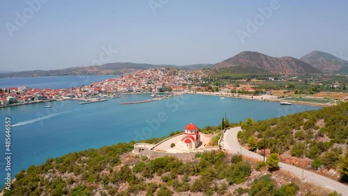 4k drone forward video (Ultra High Definition) of Ermioni port and Greek Orthodox church St. Gerasimos on foreground. Nice summer seascape of Myrtoa sea, Peloponnese, Greece, Europe. photo