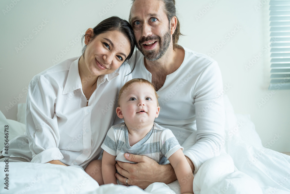 Portrait of Caucasian happy family smiling, look at camera in bedroom. 