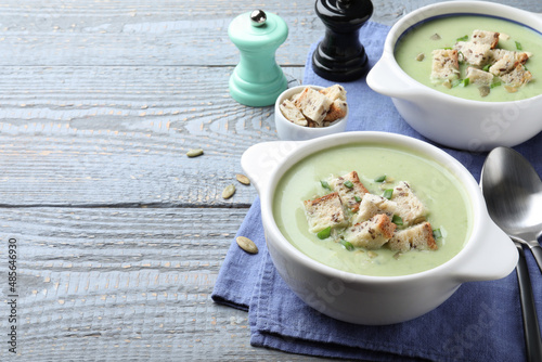 Delicious asparagus soup with croutons served on grey wooden table, space for text