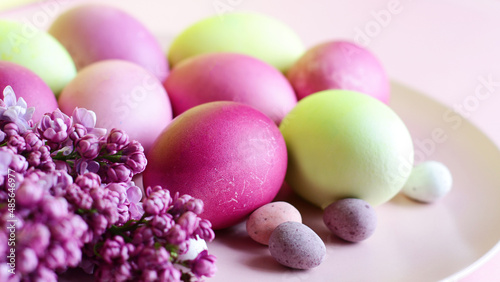 Close-up of beautiful lilac Easter eggs with blooming lilac branches. Easter decor. Selective focus.