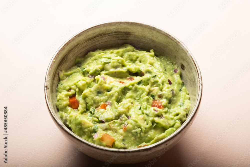 Traditional Mexican Guacamole sauce made from avocado. lime, red onion, tomatoes, cilantro on a pink background. Traditional Mexican Guacamole sauce made from avocado. lime, red onion, tomatoes, cilantro on a pink background.