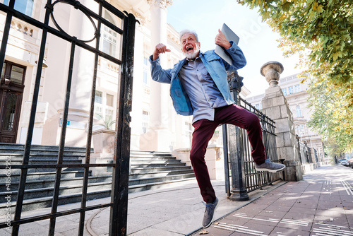 A happy senior student on the retraining program passed the exam and he is jumping with joy and happiness.
