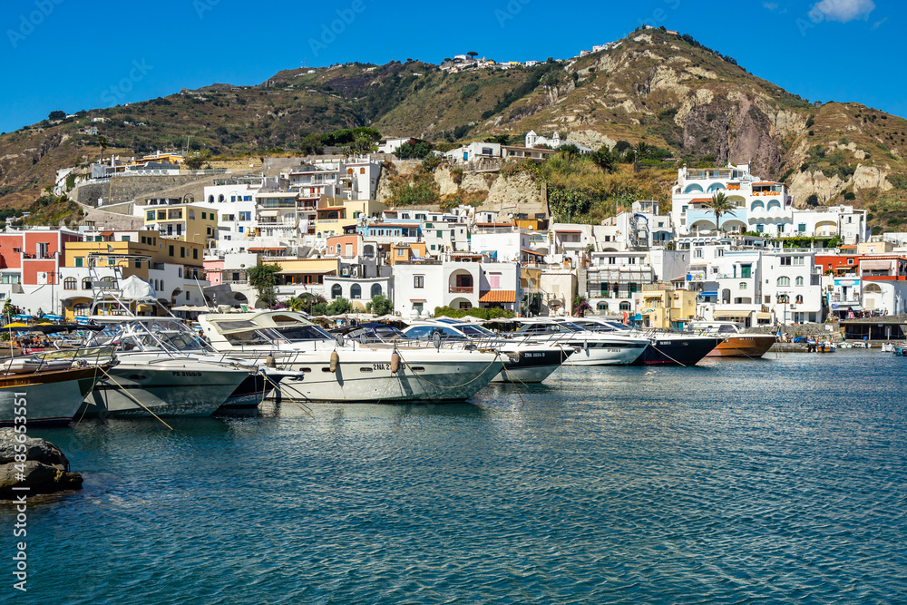 Fishing boats and speedboats moored at the colorful port of Sant’Angelo d’Ischia, Italy