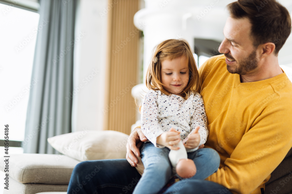 Young father having fun while playing with his little daughter on sofa at home Young father having fun while playing with his little daughter on sofa at home