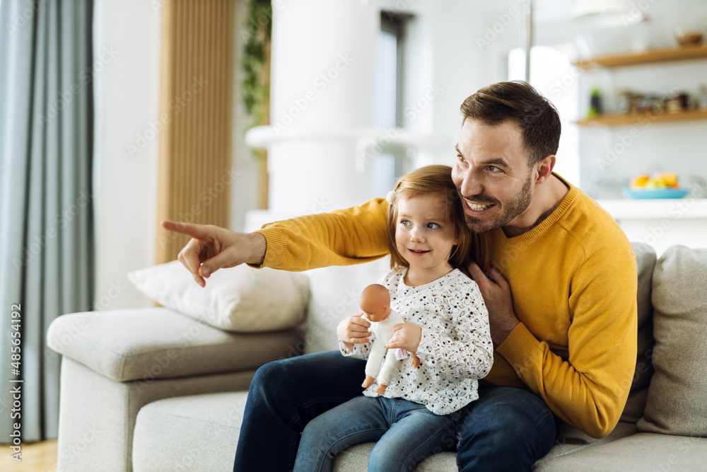 Happy father and his small daughter enjoying while watching TV on sofa in the living room Happy father and his small daughter enjoying while watching TV on sofa in the living room