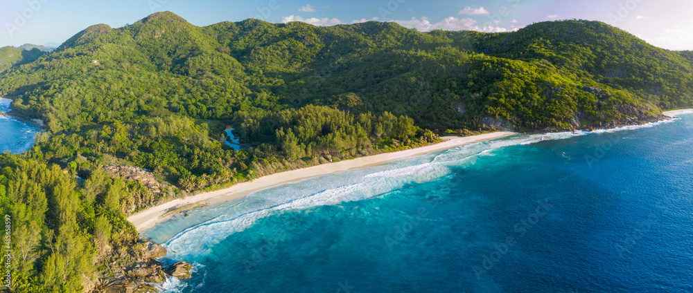 Panoramic aerial view of Police Bay and Anse Petit beach with hills in background, Takamaka, Seychelles. Panoramic aerial view of Police Bay and Anse Petit beach with hills in background, Takamaka, Seychelles.