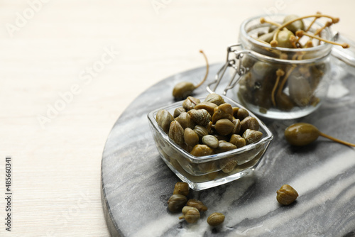 Delicious pickled capers on white wooden table, space for text