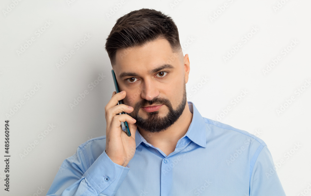Portrait of a business man with a beard talking on a mobile phone on a white background. Portrait of a business man with a beard talking on a mobile phone on a white background.