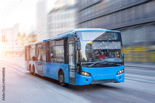 Murais de parede Blue bus moving on the road in city in early morning.