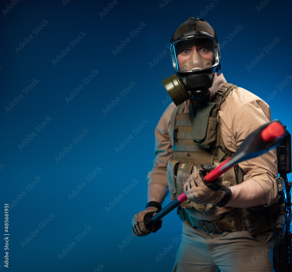 a soldier in military clothes with a bulletproof vest in a gas mask is  holding a red fire axe in his hands in fright Stock Photo | Adobe Stock