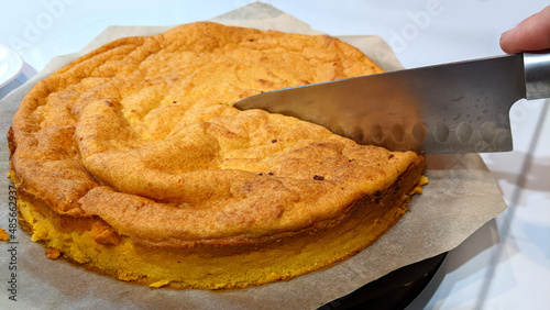 A knife cuts a delicious cottage cheese and pumpkin casserole on a black square plate on a white background