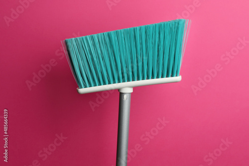 Plastic broom on pink background. Cleaning tool photo