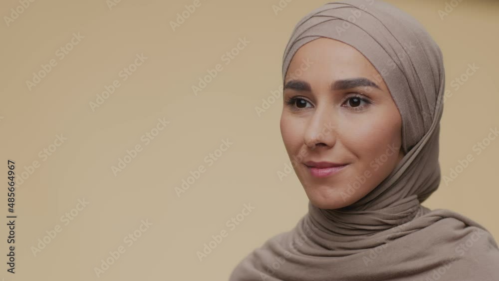 Semi profile portrait of young peaceful muslim lady in traditional hijab looking aside and softly smiling, empty space Semi profile portrait of young peaceful muslim lady in traditional hijab looking aside and softly smiling, empty space